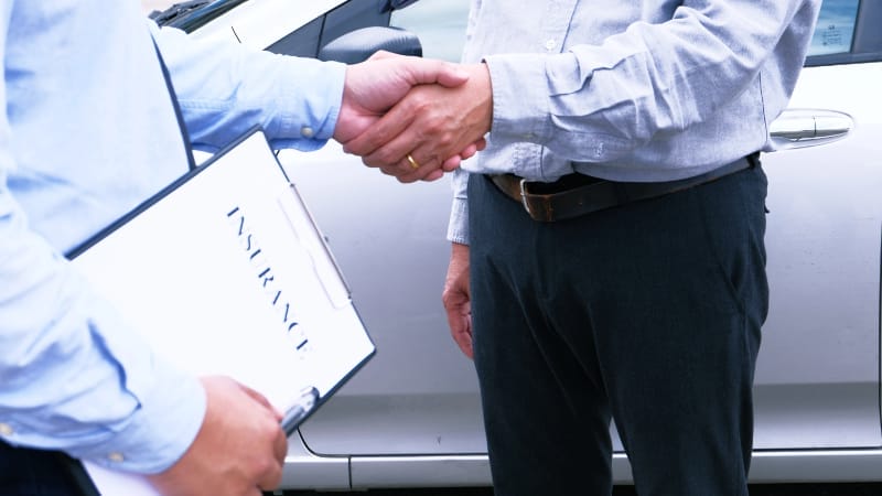Loss Adjuster Insurance Agent handshake with Inspecting Damaged Car.